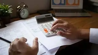 Fogli, calcolatrice, mani.