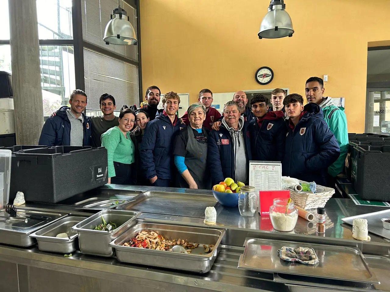 Da sinistra: mister Andrea Costa, Lorenzo Cocchi (team manager Primavera), Dario Rossi (Caritas Reggiana) insieme ai volontari e ad alcuni giovani calciatori