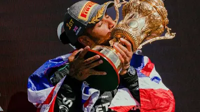 Lewis Hamilton bacia trofeo vittoria gp Silverstone 2024 F1 con bandiera regno unito