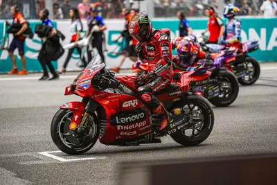 Pecco Bagnaia accarezza la moto in griglia prima del via.
