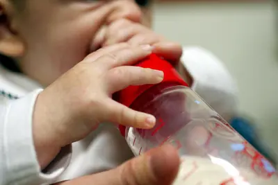 Neonato con biberon in mano