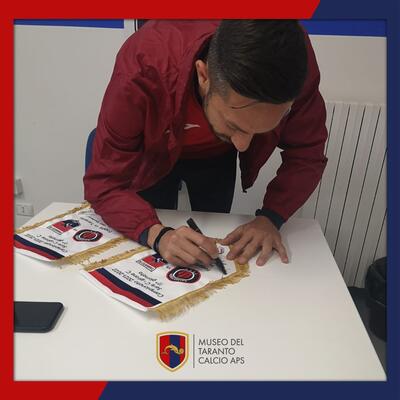 Saraniti mentre firma il gagliardetto